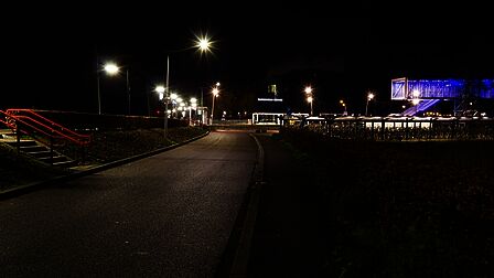 Station Barneveld Noord in de nacht. Er zijn meerdere lantaarnpalen bij de perrons. De fietsenstallingen en de traverse zijn fel verlicht. Er is geen treinverkeer meer